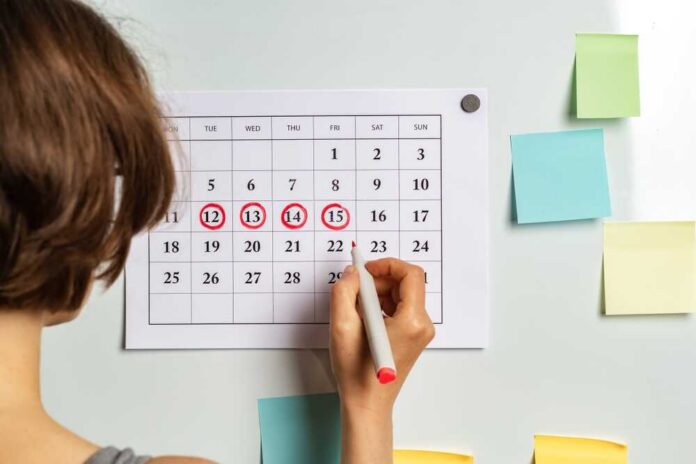 Person marking dates on a calendar with a red marker