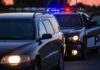 Police car with flashing lights behind a stopped vehicle at dusk