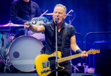 Rock Legends Clash Over Politics On Stage A musician passionately performing on stage with a guitar