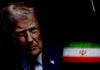 Pressure Mounts As Trump Changes Course Close-up portrait of a man with a serious expression, with the Iranian flag in the background