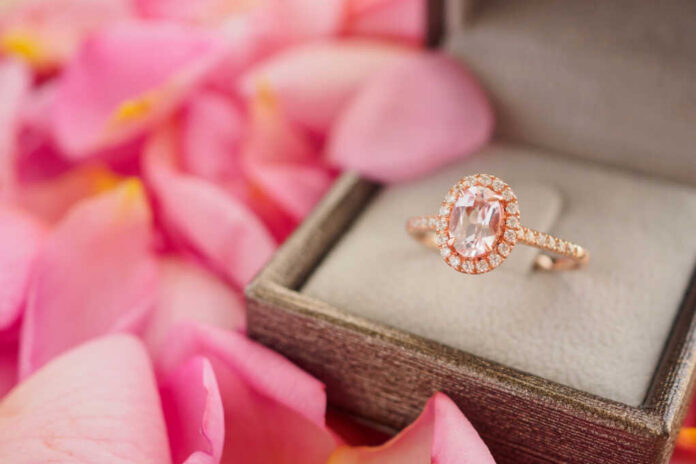 Rose gold halo ring in a jewelry box among pink petals