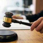 Judge's hand holding a gavel over a sound block