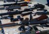 Assorted firearms and ammunition laid out on a wooden table