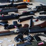 One Guilty Plea Exposes A Deadly Pipeline Assorted firearms and ammunition laid out on a wooden table