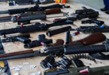 Assorted firearms and ammunition laid out on a wooden table