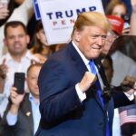 Trump’s 2028 Tease Has One Giant Problem man in suit raising fists at a rally podium
