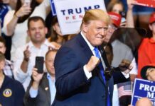 Trump’s 2028 Tease Has One Giant Problem man in suit raising fists at a rally podium