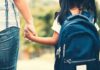 Child with backpack holding adult's hand