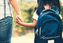 Child with backpack holding adult's hand