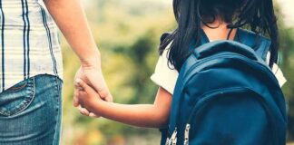 Child with backpack holding adult's hand