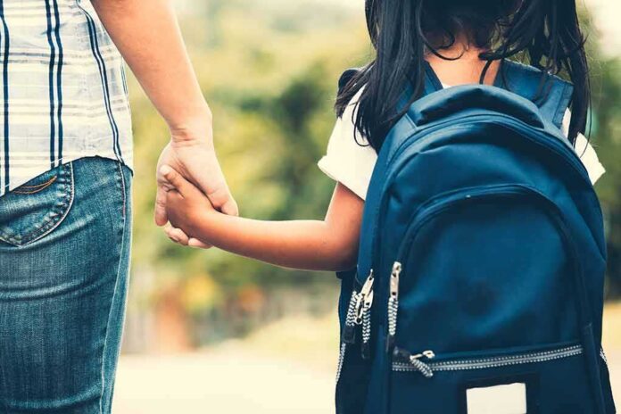 Child with backpack holding adult's hand