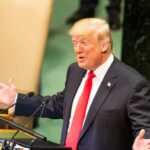 speaker in suit gestures at podium