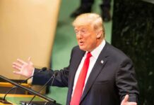 speaker in suit gestures at podium