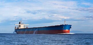 A large cargo ship sailing on the ocean under a blue sky