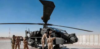 Soldiers inspect a military attack helicopter on a tarmac