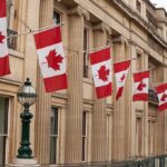 Deal Tease at Midnight — Tariffs On Ice Canadian flags on a neoclassical building facade