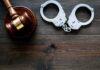 Gavel and handcuffs on wooden table
