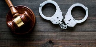 Gavel and handcuffs on wooden table