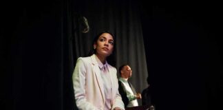 Woman in a white suit sitting backstage with a folder