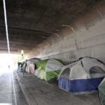 Twelve Camping Restrictions Just Disappeared Overnight Tents lined up under a concrete overpass