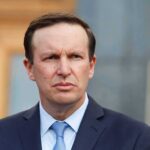 Dem Senator Turns Politics Into a Spiritual Diagnosis Man in suit and tie outdoors with serious expression