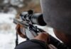 Wild Sniper Claim Ignites Record War person aiming a rifle with a scope outdoors