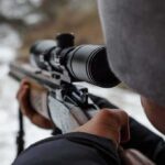 Wild Sniper Claim Ignites Record War person aiming a rifle with a scope outdoors
