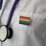 A Healthcare Promise With No Age Line stethoscope on white lab coat with rainbow pin