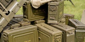 Stack of green military ammunition boxes on grass