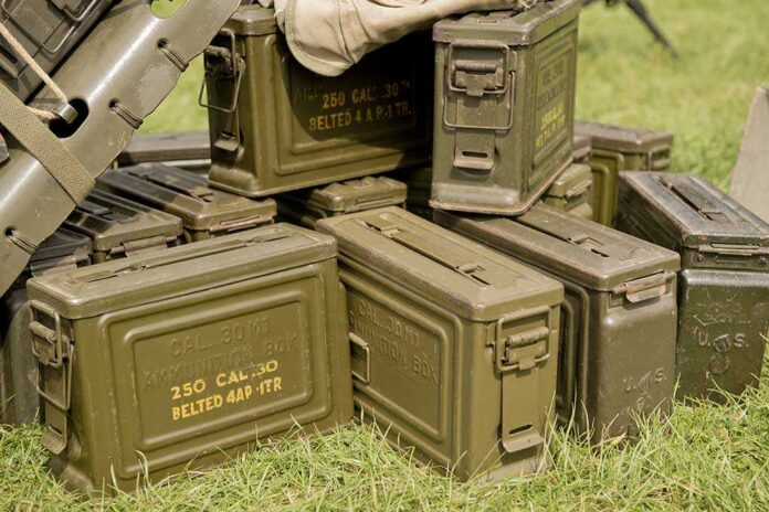Stack of green military ammunition boxes on grass