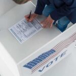 One Checked Box Lands A Registrant In Trouble Voter filling out a ballot in a private voting booth