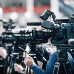 Election Rules? One Check Blows Them Up Broadcast cameras on tripods at a press event
