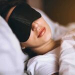 This Part of Sleep Tracks With 83 Diseases Woman sleeping with a black eye mask in bed
