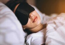 This Part of Sleep Tracks With 83 Diseases Woman sleeping with a black eye mask in bed