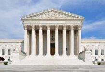 Supreme Court Keeps Mail Ballot Rules Intact Front view of the Supreme Court building with large columns and steps under a blue sky