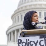 Ilhan Omar speaking at a podium with microphones in front of the U.S. Capitol