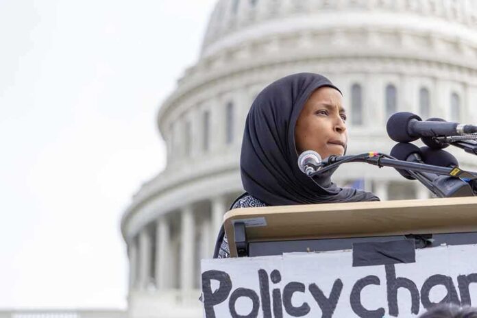 shutterstock_1355305115 Ilhan Omar speaking at a podium with microphones in front of the U.S. Capitol