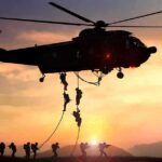 military helicopter with soldiers fast-roping at sunset