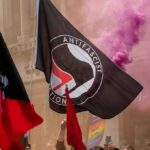 Germany’s Political Divide Boiled Into The Streets protesters with antifascist flags and purple smoke