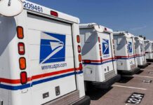 Row of USPS mail trucks parked in a lot