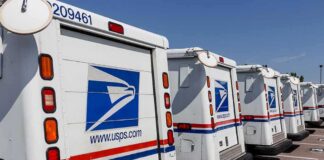 Row of USPS mail trucks parked in a lot