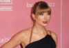 New Honor Crowns Swift’s VMA Takeover Taylor Swift on a pink carpet in a black dress with gold chain straps