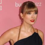 New Honor Crowns Swift’s VMA Takeover Taylor Swift on a pink carpet in a black dress with gold chain straps