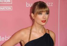 New Honor Crowns Swift’s VMA Takeover Taylor Swift on a pink carpet in a black dress with gold chain straps