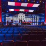 Fallon Turns Iran Crisis Into Trump Punchline Debate stage with red and blue lighting and empty audience seats