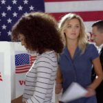 The Numbers Behind America’s Noncitizen Voting Fight Voters at polling booths in front of an American flag