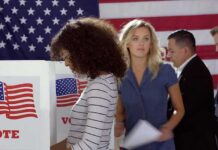 Voters at polling booths in front of an American flag
