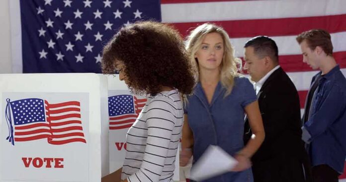 Voters at polling booths in front of an American flag