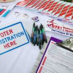 Federal Judge Limits Election Records Request Voter registration table with forms, pens, and informational materials