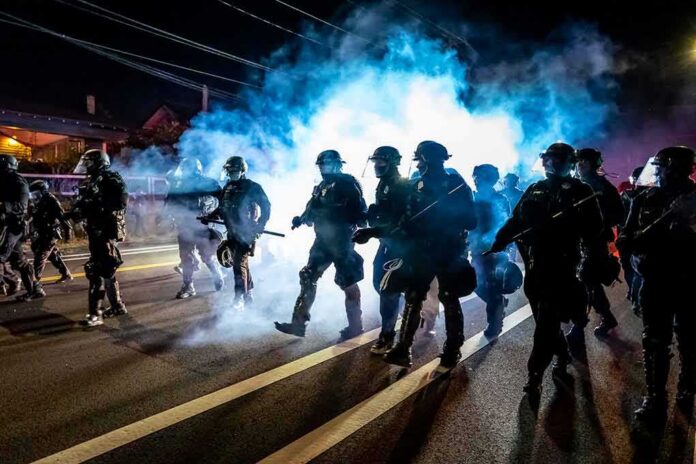 Riot police advance through tear gas at night on a city street